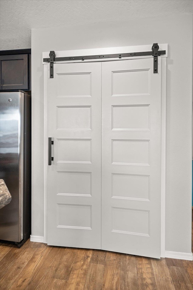 interior space with hardwood / wood-style flooring, stainless steel fridge, and a barn door