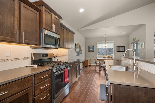 kitchen featuring vaulted ceiling, decorative light fixtures, stainless steel appliances, tasteful backsplash, and sink