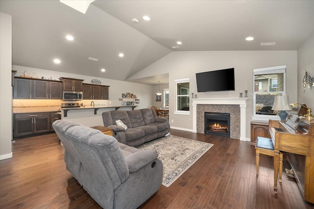 living room featuring lofted ceiling, a tile fireplace, and dark hardwood / wood-style floors