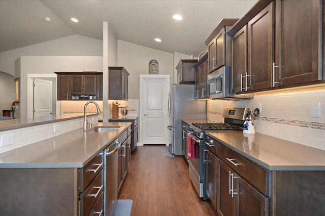 kitchen with dark wood-type flooring, vaulted ceiling, stainless steel appliances, decorative backsplash, and sink