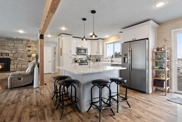 kitchen featuring decorative light fixtures, white cabinets, light hardwood / wood-style floors, and appliances with stainless steel finishes