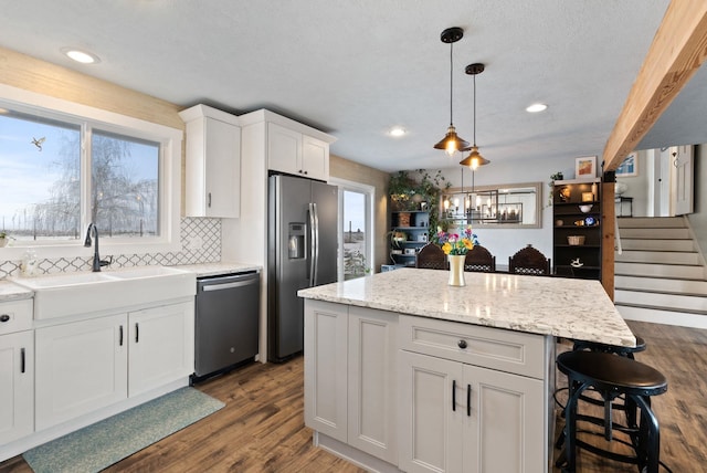 kitchen featuring tasteful backsplash, a kitchen island, white cabinetry, appliances with stainless steel finishes, and sink