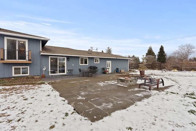 snow covered rear of property with a fire pit and a patio