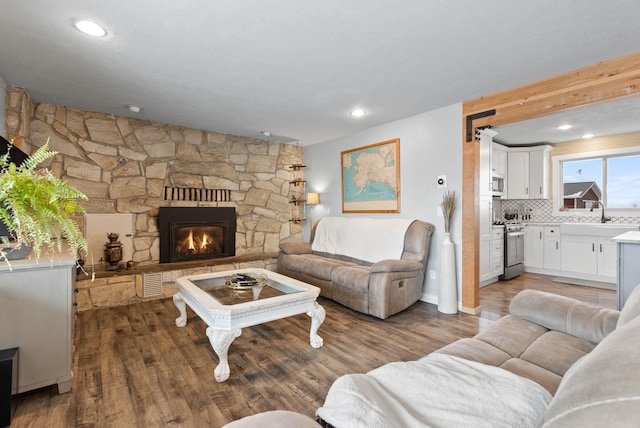 living room featuring a stone fireplace and hardwood / wood-style floors