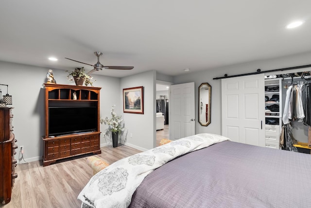 bedroom with ceiling fan, light hardwood / wood-style floors, and a barn door