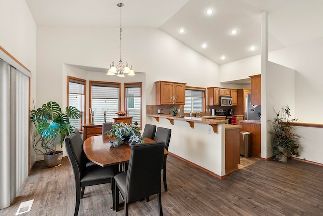 dining area featuring dark hardwood / wood-style flooring, high vaulted ceiling, and a chandelier