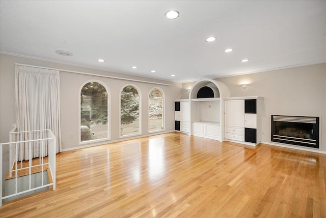 unfurnished living room with light wood-type flooring and ornamental molding