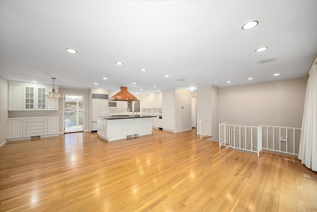 unfurnished living room featuring an inviting chandelier and light wood-type flooring