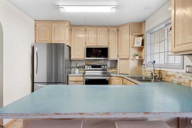 kitchen featuring stainless steel appliances, light tile patterned floors, light brown cabinetry, sink, and backsplash