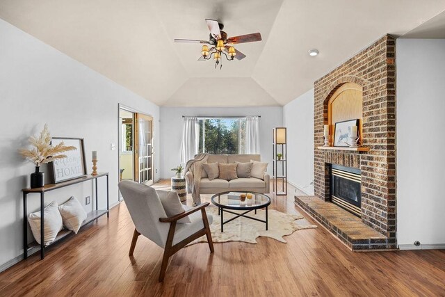 living room featuring ceiling fan, lofted ceiling, a fireplace, and hardwood / wood-style flooring