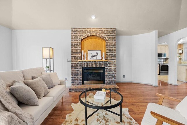 living room with ceiling fan, hardwood / wood-style floors, lofted ceiling, and a fireplace