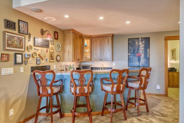 kitchen with a breakfast bar area, light carpet, a healthy amount of sunlight, and a notable chandelier