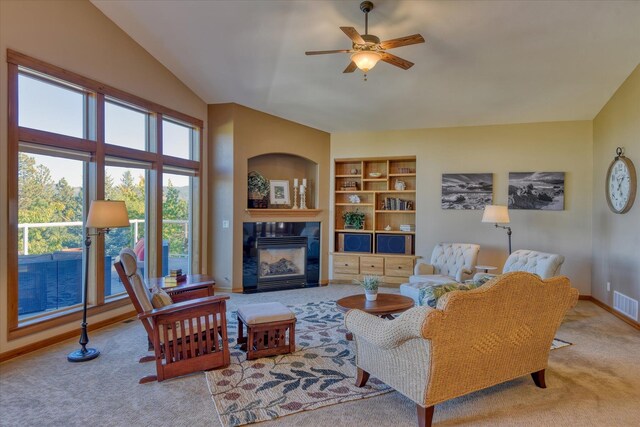 living room featuring a tiled fireplace, light hardwood / wood-style floors, lofted ceiling with beams, sink, and ceiling fan with notable chandelier