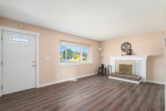 unfurnished living room featuring dark wood-type flooring and a tile fireplace