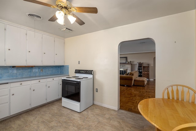 kitchen featuring white cabinets, a fireplace, ceiling fan, decorative backsplash, and range with electric stovetop