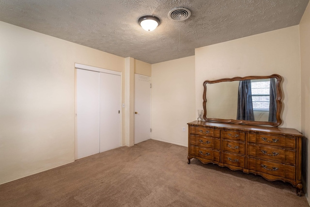 unfurnished bedroom featuring a closet, a textured ceiling, and light carpet