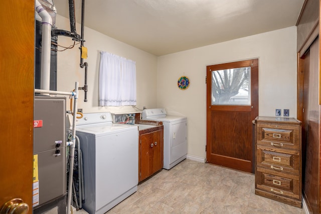 clothes washing area featuring washing machine and clothes dryer, plenty of natural light, and cabinets