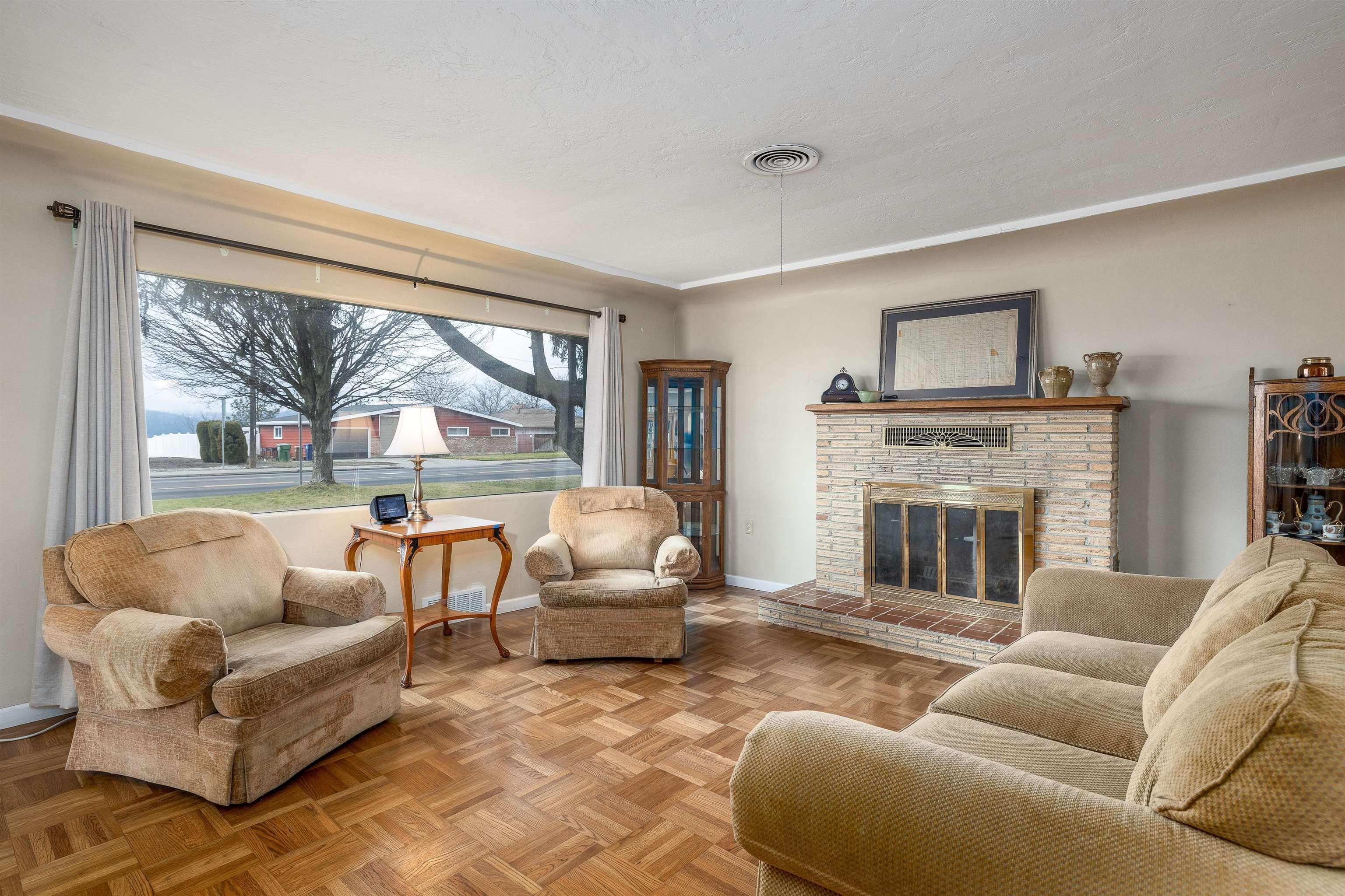 living room featuring light parquet flooring, a textured ceiling, and a brick fireplace