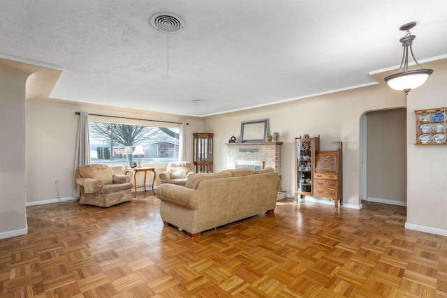 living room with a textured ceiling, parquet flooring, and a stone fireplace