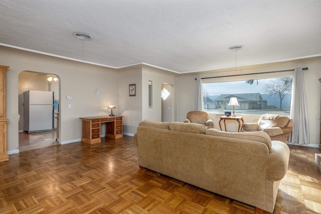 living room featuring ornamental molding, a textured ceiling, ceiling fan, and parquet flooring