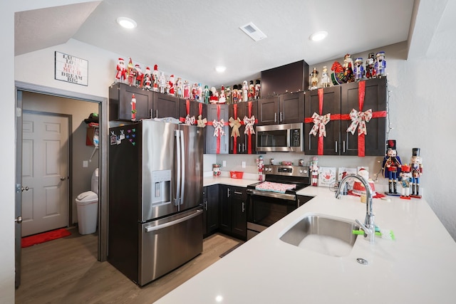 kitchen with stainless steel appliances, lofted ceiling, light wood-type flooring, backsplash, and sink