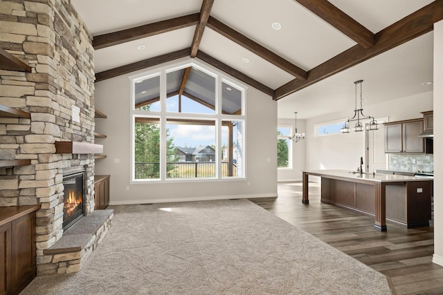 unfurnished living room with a notable chandelier, plenty of natural light, a fireplace, and sink