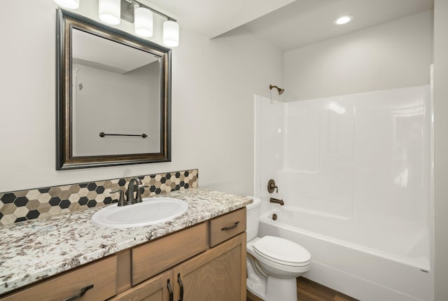 full bathroom featuring tasteful backsplash, toilet, wood-type flooring, washtub / shower combination, and vanity