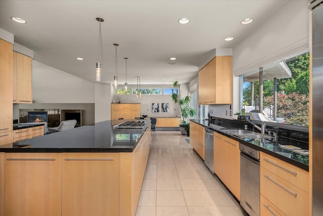 kitchen with hanging light fixtures, a center island, light brown cabinetry, appliances with stainless steel finishes, and sink