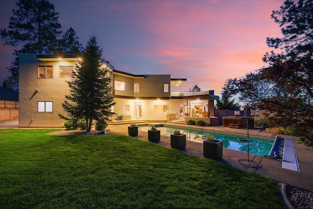 pool at dusk with a lawn and a patio area