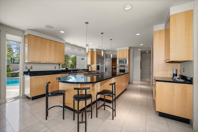 kitchen with hanging light fixtures, a center island, built in appliances, a breakfast bar, and light tile patterned flooring