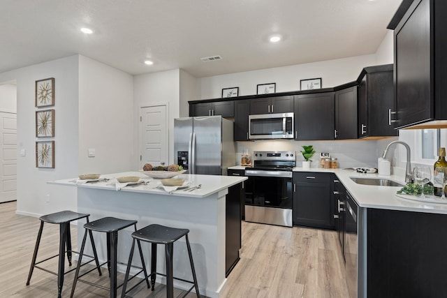 3122 N Glenrose Rd, Spokane, WA 99217 - kitchen with appliances with stainless steel finishes, a breakfast bar area, dark cabinets, light wood-type flooring, and recessed lighting