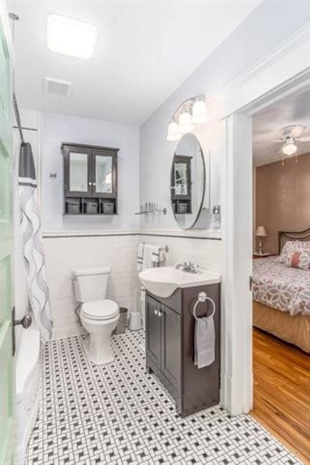 bathroom with toilet, ceiling fan, tile walls, and vanity