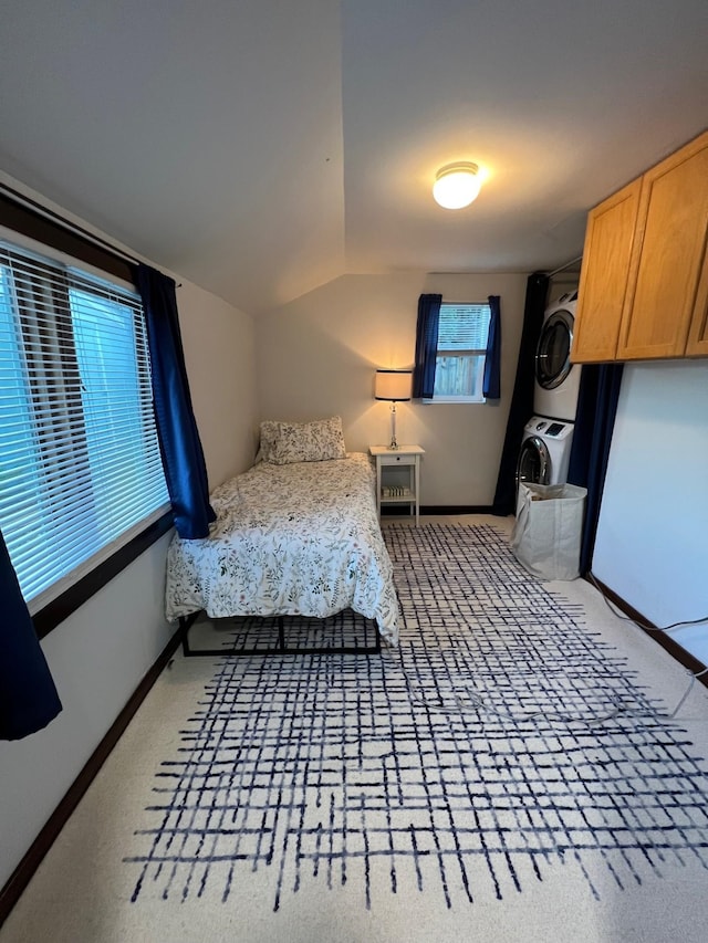 bedroom with stacked washer and clothes dryer, carpet flooring, and vaulted ceiling