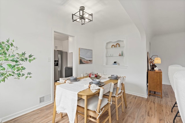 dining area featuring a notable chandelier, light hardwood / wood-style flooring, and built in features