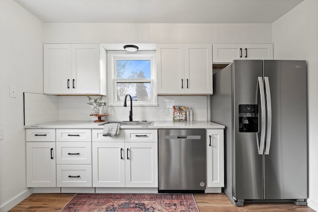 kitchen with sink, appliances with stainless steel finishes, backsplash, and white cabinetry