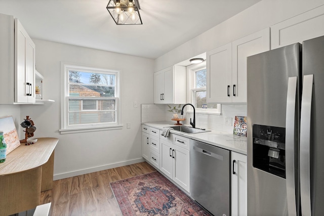 kitchen with stainless steel appliances, sink, white cabinets, hardwood / wood-style flooring, and tasteful backsplash