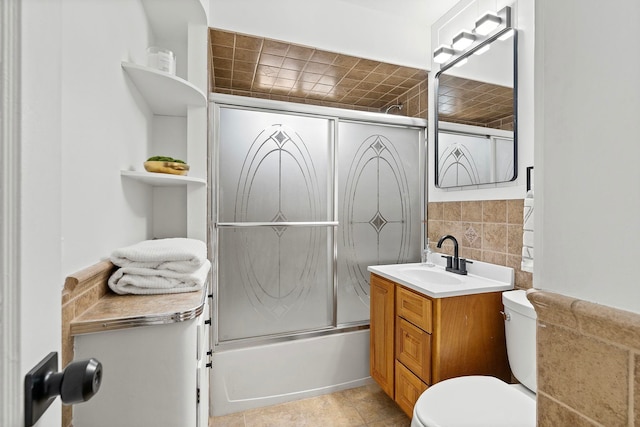 full bathroom with toilet, tasteful backsplash, combined bath / shower with glass door, tile walls, and vanity