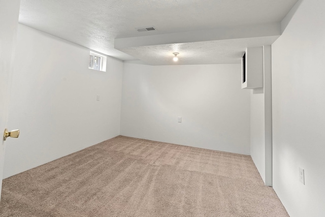 basement featuring a textured ceiling and light carpet