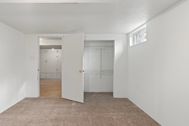 unfurnished bedroom with a closet, light carpet, and a textured ceiling