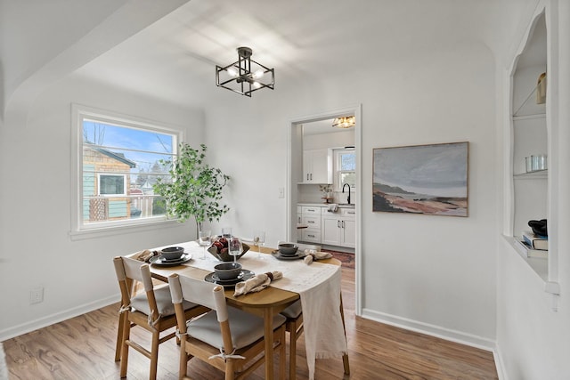 dining space featuring sink, a notable chandelier, and hardwood / wood-style floors