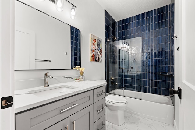 full bathroom featuring toilet, a textured ceiling, tiled shower / bath, and vanity