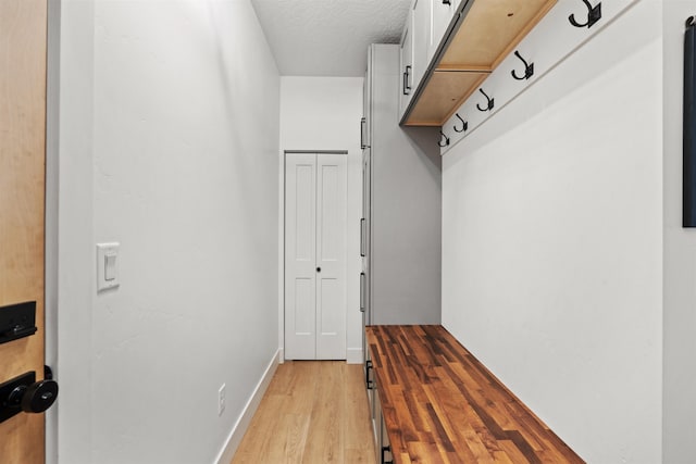 mudroom with light hardwood / wood-style floors and a textured ceiling