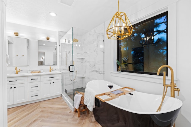 bathroom featuring an inviting chandelier, parquet flooring, plus walk in shower, and vanity