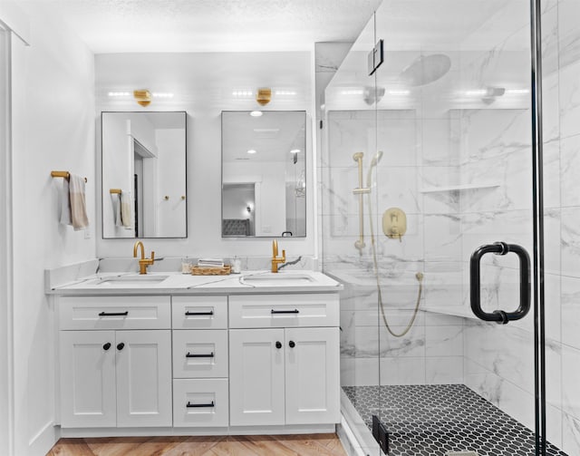 bathroom featuring vanity, a textured ceiling, and a shower with shower door