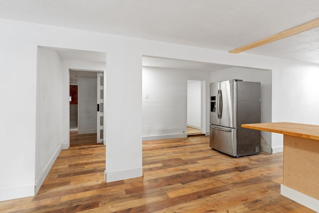 kitchen with wooden counters, hardwood / wood-style flooring, and stainless steel fridge