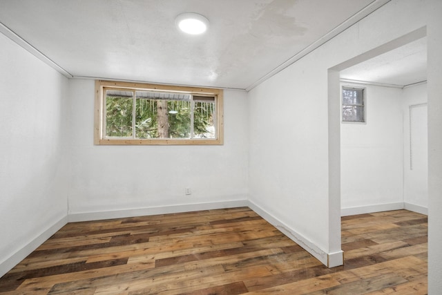 empty room with ornamental molding and dark wood-type flooring