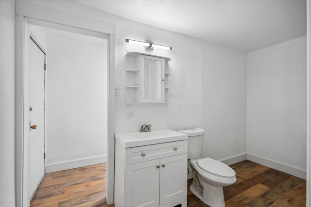 bathroom with toilet, vanity, and hardwood / wood-style floors