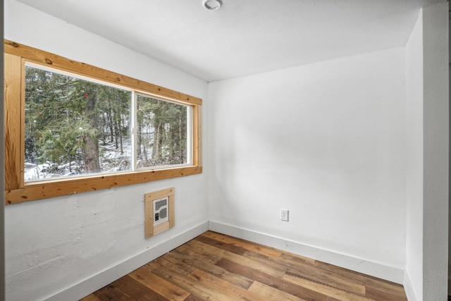 unfurnished room featuring heating unit, hardwood / wood-style flooring, and a wealth of natural light