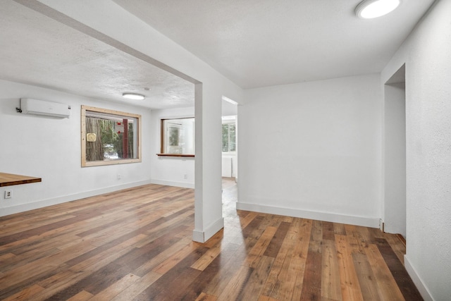 interior space with a textured ceiling, dark hardwood / wood-style floors, and a wall mounted AC