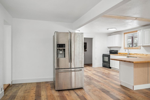 kitchen featuring stainless steel fridge, light hardwood / wood-style floors, wood counters, black range with electric stovetop, and white cabinets